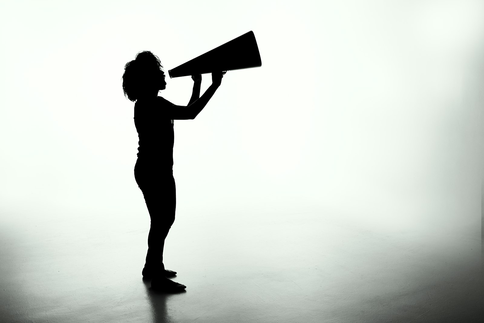 Silhouette en noir et blanc d’une personne lançant un appel dans un mégaphone.