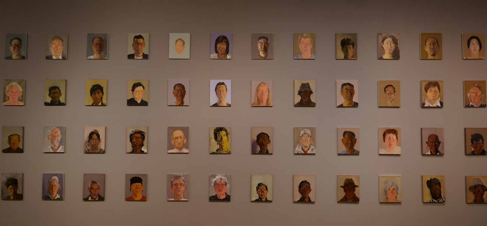 Mur de nombreux portraits peints, diversifiés en âge et en origine, évoquant un panel de profils.