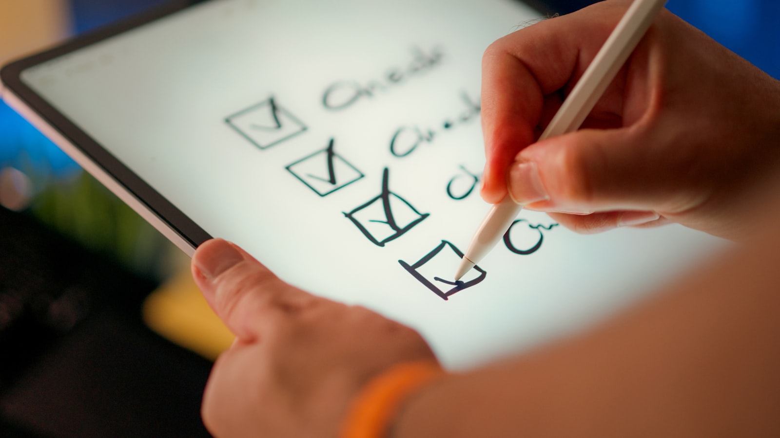 Main cochant une liste de contrôle sur une tablette, au stylet.