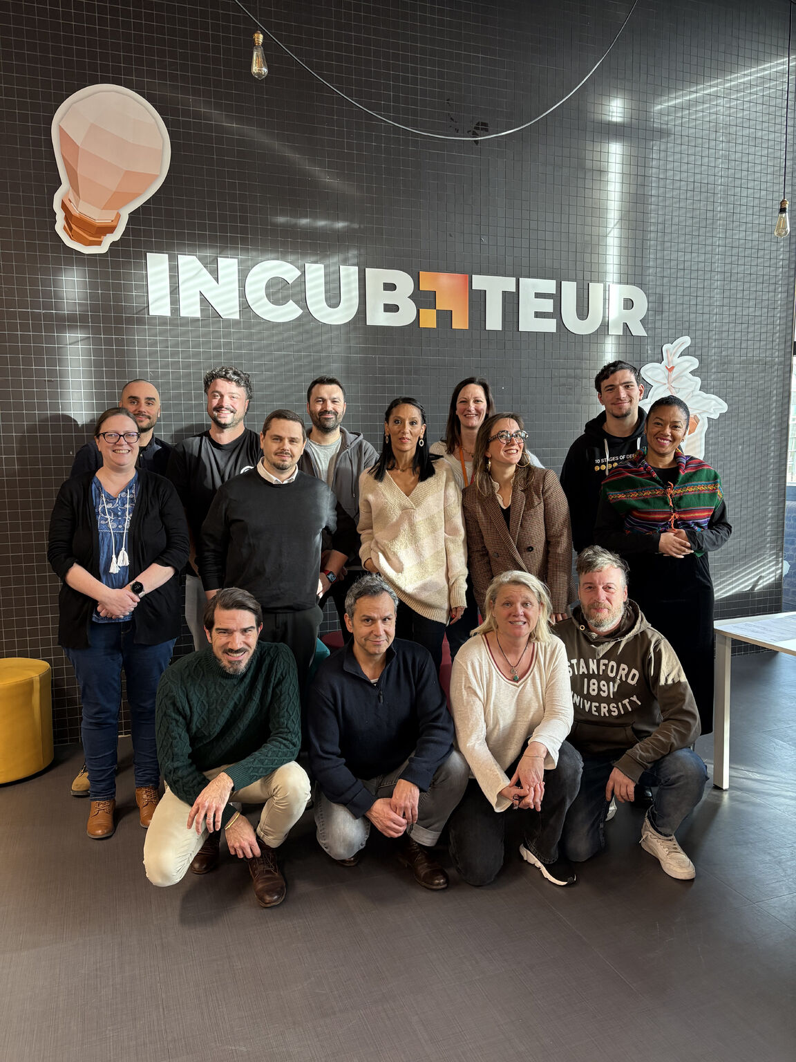 Photo de groupe de la cohorte de pré-incubation devant le mur « Incubateur » d’EuraTechnologies à Lille.